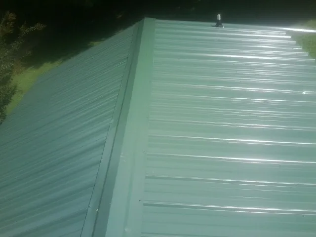 New green metal panels meeting at the ridge of a roof — Flat Roof Repair work by our crew in Advent