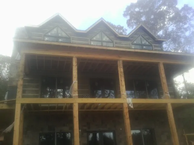 Dormers and porch framing on a large log home under construction — Roof Coating work by our crew in Advent