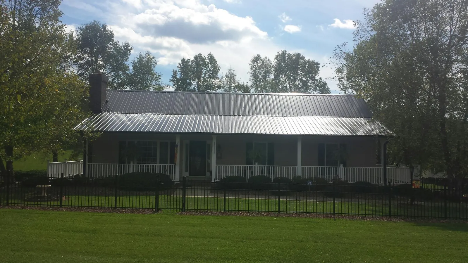 Gray metal roof on a brick ranch with a full width front porch — Gutter Guard Installation work by our crew in Advent